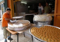 A Palestinian boy arranges traditional cookies in a box to be sold in Nablus, ahead of Eid al-Adha
